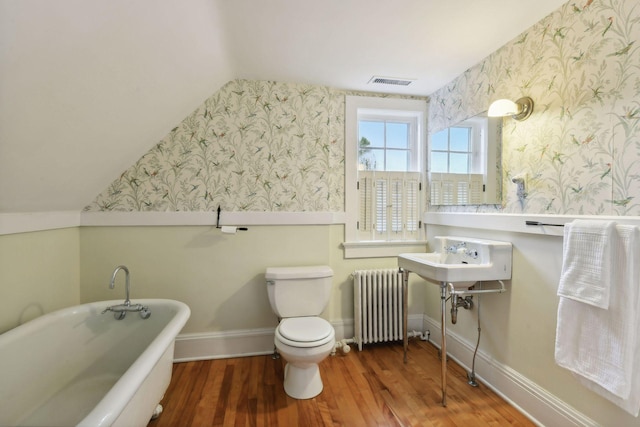 bathroom with radiator heating unit, wood-type flooring, lofted ceiling, a bathtub, and toilet