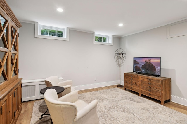 sitting room with ornamental molding and light wood-type flooring