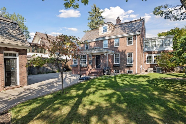 back of property featuring a lawn and central air condition unit