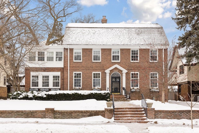 colonial home with brick siding and a chimney