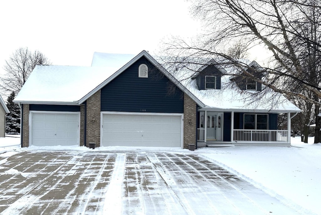 view of front facade featuring an attached garage, driveway, a porch, and brick siding