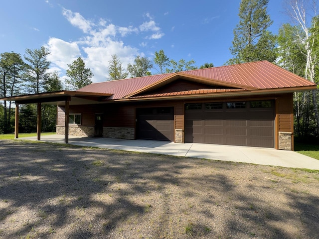 view of front of house featuring stone siding, aphalt driveway, an attached garage, and metal roof