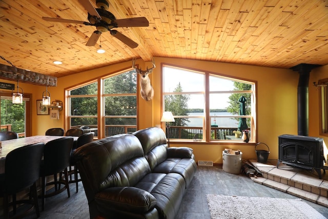 living area featuring visible vents, ceiling fan, wood ceiling, and a wood stove