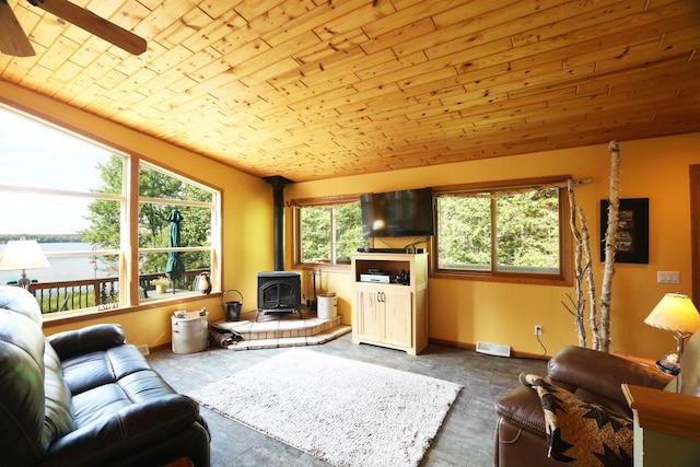 living room featuring visible vents, ceiling fan, lofted ceiling, a wood stove, and wood ceiling