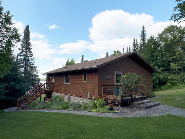 back of property with a lawn, a wooden deck, and stairway