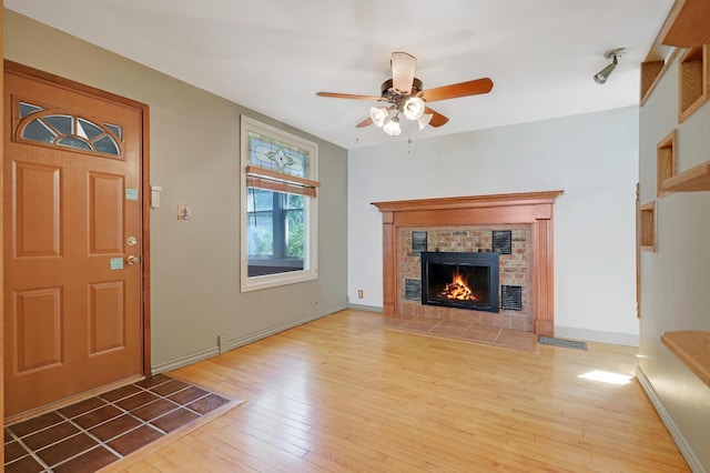 foyer featuring a fireplace, ceiling fan, and light wood-type flooring