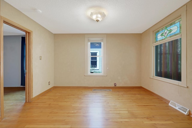 spare room with light hardwood / wood-style flooring and a textured ceiling