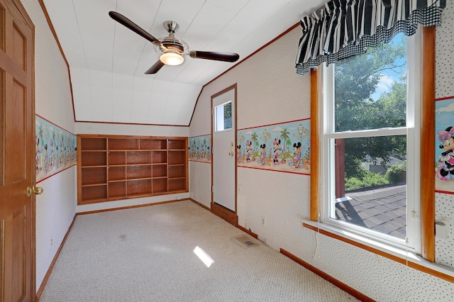 empty room with ceiling fan, lofted ceiling, a healthy amount of sunlight, and light colored carpet