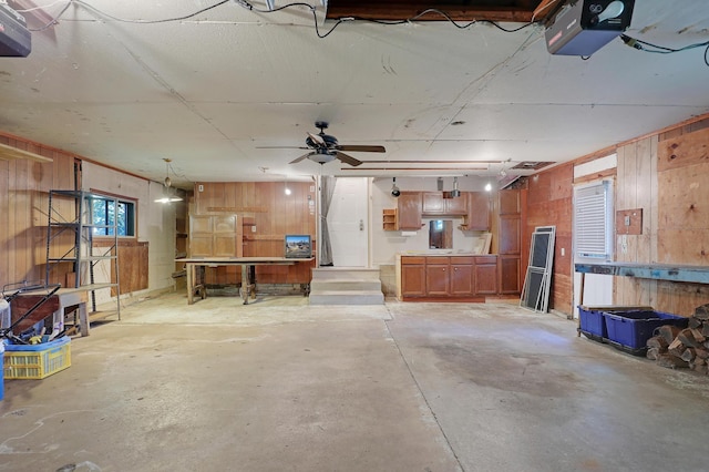 garage featuring ceiling fan, a garage door opener, and wood walls