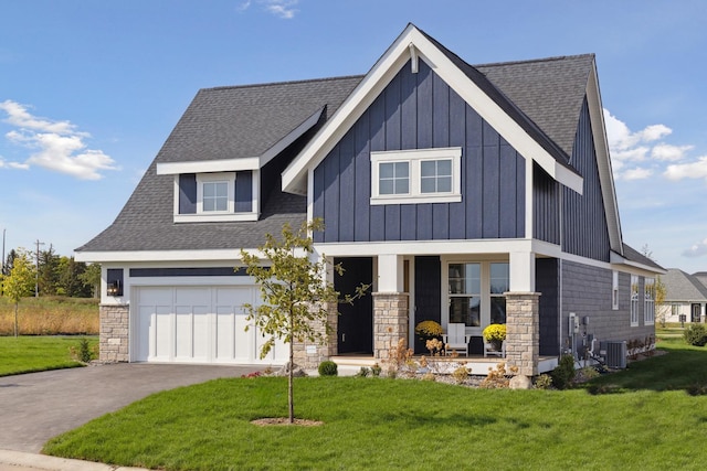 view of front of house featuring cooling unit, a porch, a garage, and a front lawn