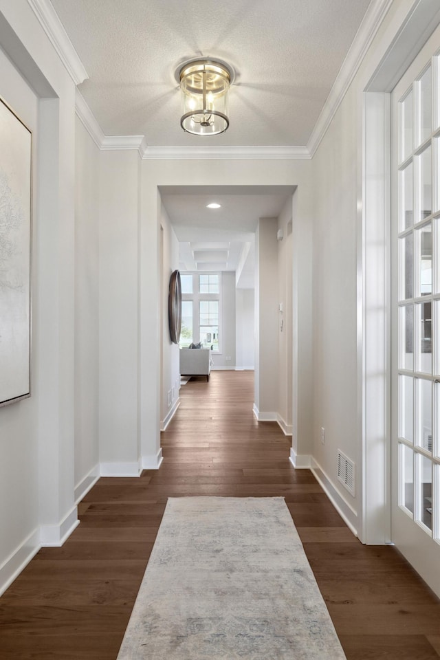 corridor with crown molding, dark hardwood / wood-style floors, an inviting chandelier, and a textured ceiling