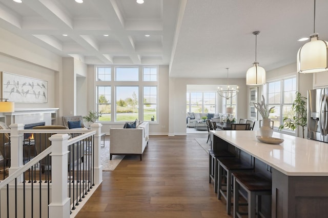 kitchen with pendant lighting, stainless steel fridge, dark hardwood / wood-style floors, coffered ceiling, and beamed ceiling