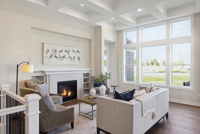 living area with dark wood finished floors, a glass covered fireplace, coffered ceiling, beamed ceiling, and baseboards