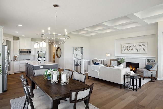 dining area with a warm lit fireplace, dark wood-type flooring, coffered ceiling, and recessed lighting