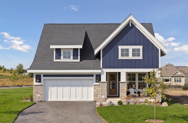 view of front of house featuring aphalt driveway, a shingled roof, board and batten siding, a front yard, and stone siding