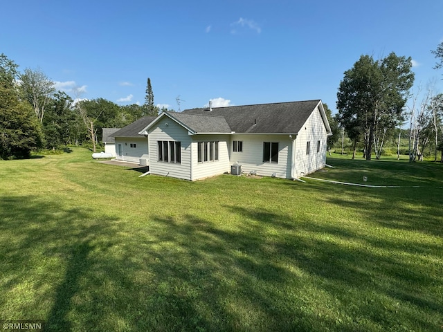 rear view of property with cooling unit and a lawn