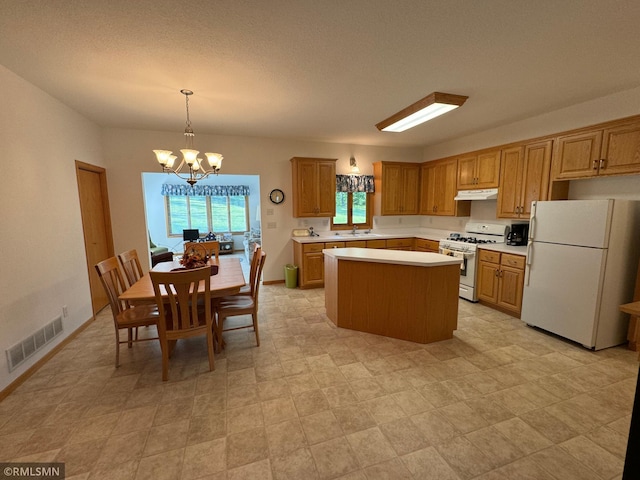 kitchen featuring a kitchen island, white appliances, sink, hanging light fixtures, and an inviting chandelier