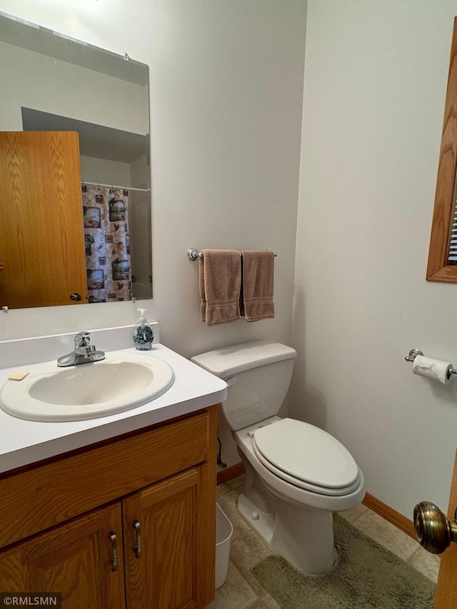 bathroom with tile patterned flooring, walk in shower, vanity, and toilet