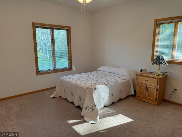 carpeted bedroom featuring multiple windows and ceiling fan