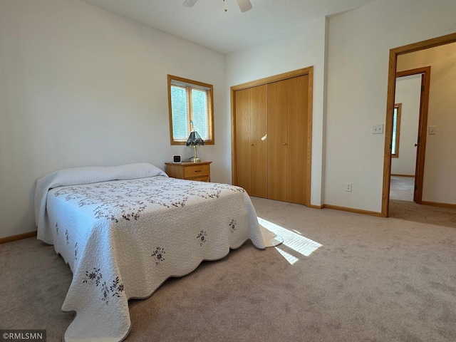 bedroom with ceiling fan, light colored carpet, and a closet