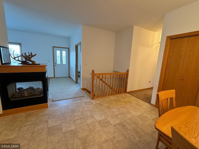 foyer entrance with light carpet and a multi sided fireplace