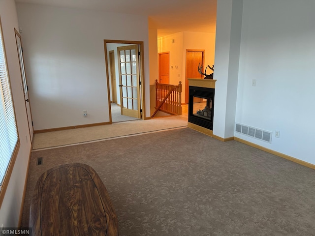 spare room with plenty of natural light, carpet floors, and a multi sided fireplace