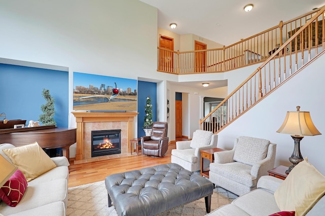 living room with light hardwood / wood-style floors, a fireplace, and a towering ceiling