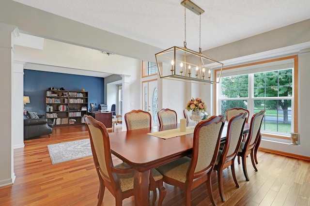 dining area featuring a notable chandelier, light wood-type flooring, and a textured ceiling