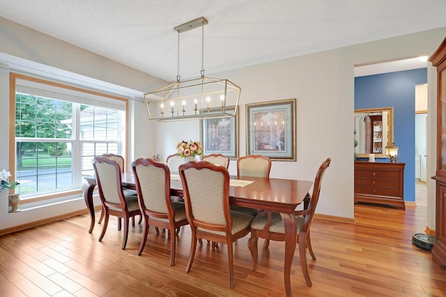 dining room featuring a textured ceiling, light hardwood / wood-style flooring, and a chandelier