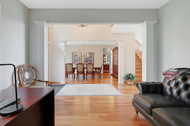 living room with light wood-type flooring, decorative columns, and a chandelier