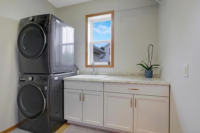 laundry room featuring cabinets, stacked washer / drying machine, and sink