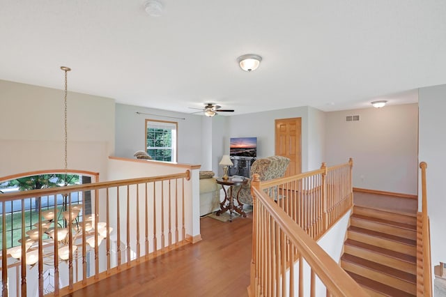 corridor with hardwood / wood-style floors and a notable chandelier