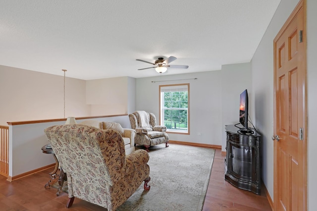 living room featuring ceiling fan, a textured ceiling, and hardwood / wood-style floors