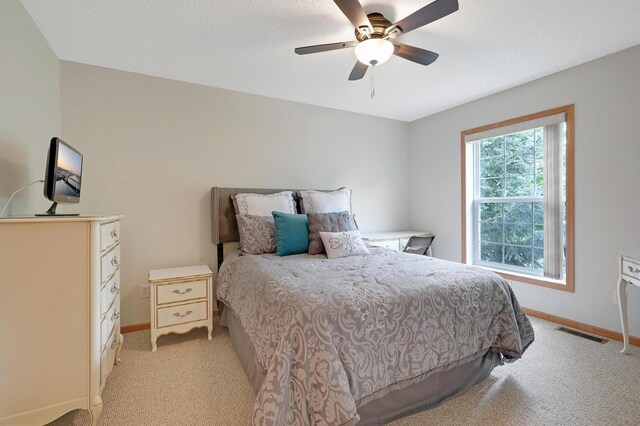 carpeted bedroom with ceiling fan and a textured ceiling