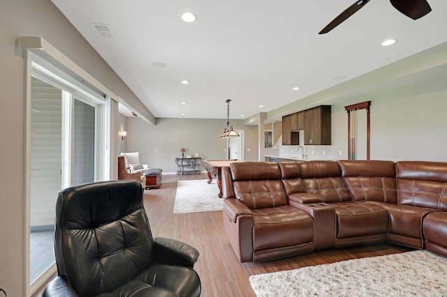 living room featuring light wood-type flooring, ceiling fan, and sink