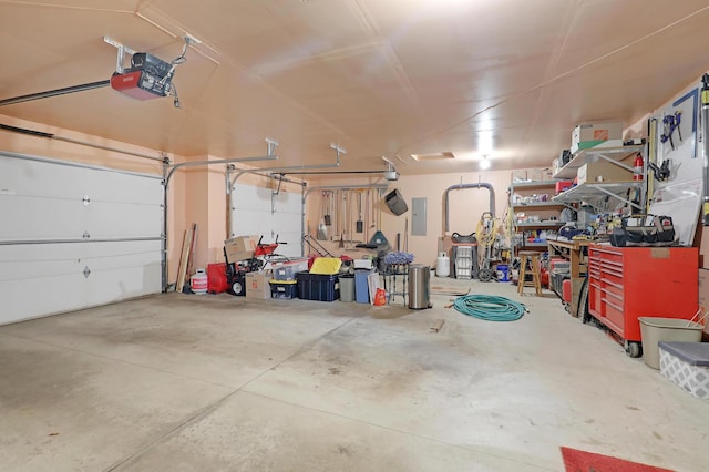 garage with a garage door opener, a workshop area, and electric panel