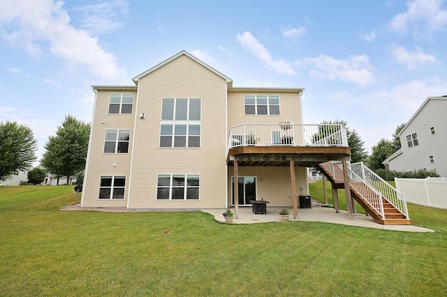 back of property with a deck, a lawn, and a patio