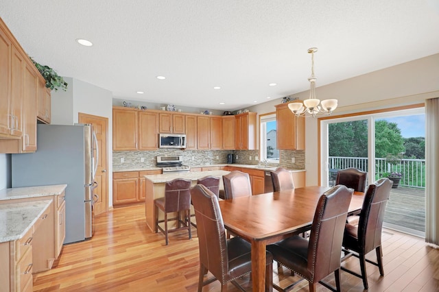 dining space featuring light wood-type flooring, a textured ceiling, sink, and a chandelier