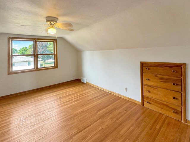 bonus room featuring lofted ceiling, light hardwood / wood-style floors, a textured ceiling, and ceiling fan