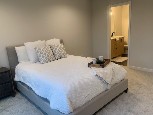 carpeted bedroom featuring ensuite bathroom and sink