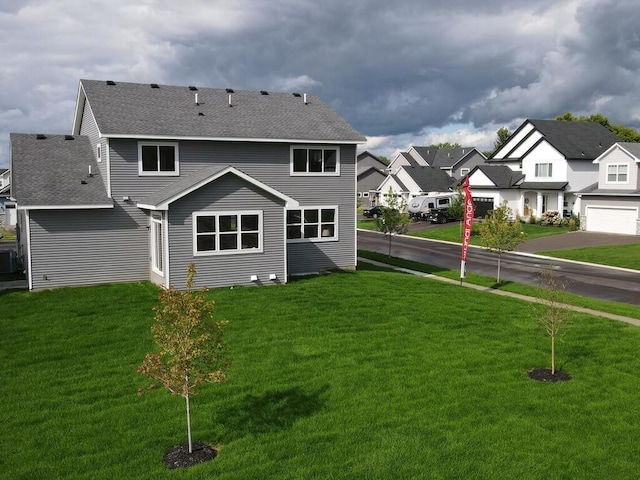 rear view of property featuring a shingled roof, a residential view, a lawn, and central AC unit