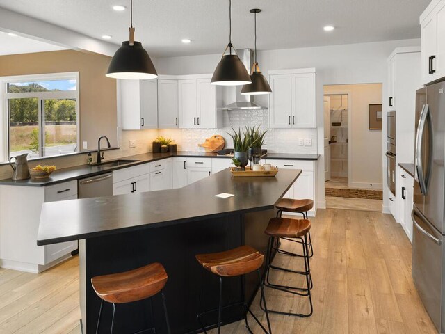 kitchen with a sink, dark countertops, stainless steel appliances, light wood-type flooring, and recessed lighting