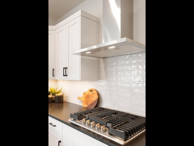 kitchen with white cabinetry, stainless steel gas cooktop, tasteful backsplash, and wall chimney range hood