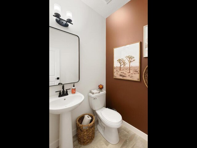 bathroom with toilet, baseboards, and a sink
