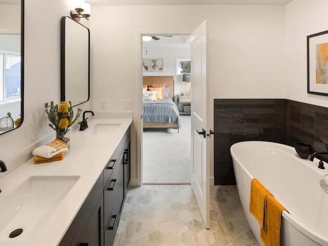 bathroom with tile patterned floors, vanity, tile walls, a bath, and ceiling fan