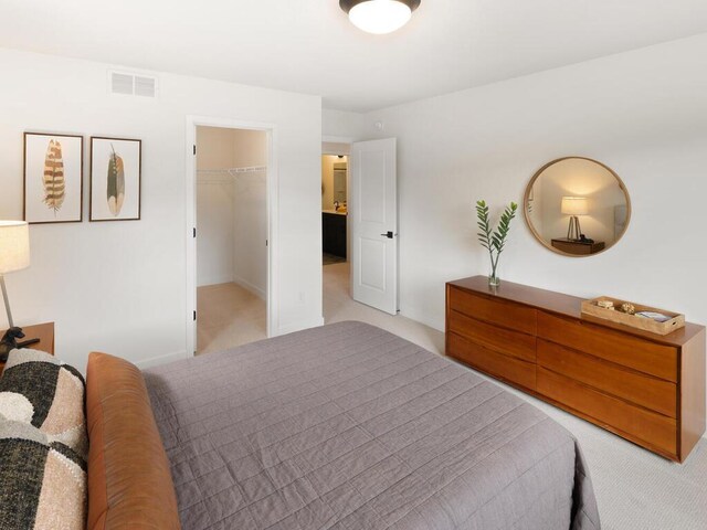 bedroom featuring light colored carpet and a walk in closet