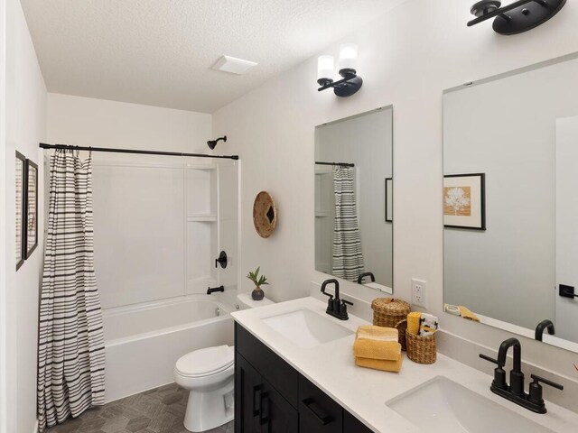 full bath featuring toilet, a textured ceiling, shower / tub combo with curtain, and double vanity