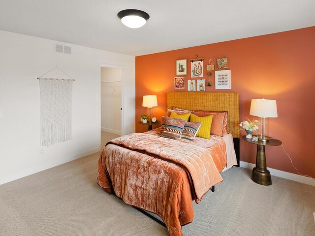 carpeted bedroom featuring a spacious closet, baseboards, and a closet