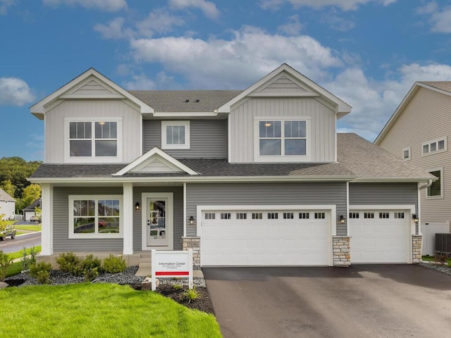 view of front of house with board and batten siding, driveway, an attached garage, and roof with shingles