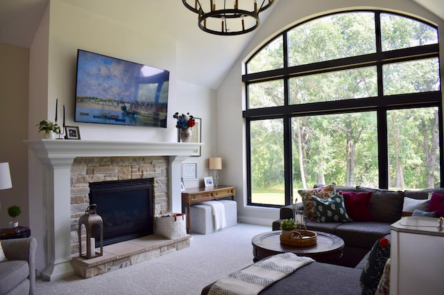 carpeted living room with a stone fireplace, high vaulted ceiling, and a chandelier